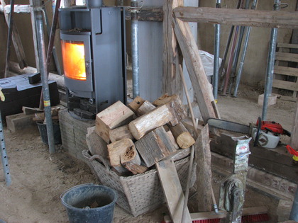 Die Kettensäge rechts sorgt für Feuerholz mitte welches im Ofen links verbrannt wird