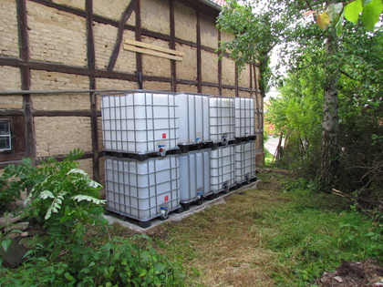 Die Regenwassercontainer IBC 1000L Tanks hinter der Scheune