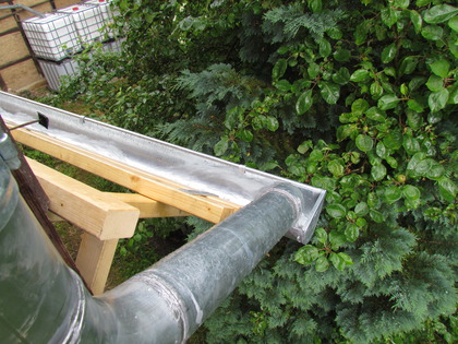 Das Regenwasser schiesst aus dem Fallrohr in die Dachrinne