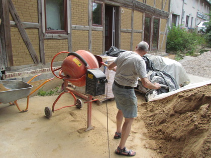 Harry wirft Innenputzsand in den Betonmischer