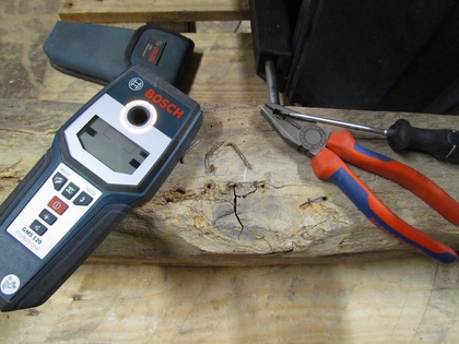Multidetektor nebst Nagelfund und Werkzeug auf altem Holzbalken