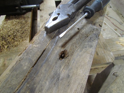 Nagel im Holz wird mit dem Schraubendreher und der Zange entfernt